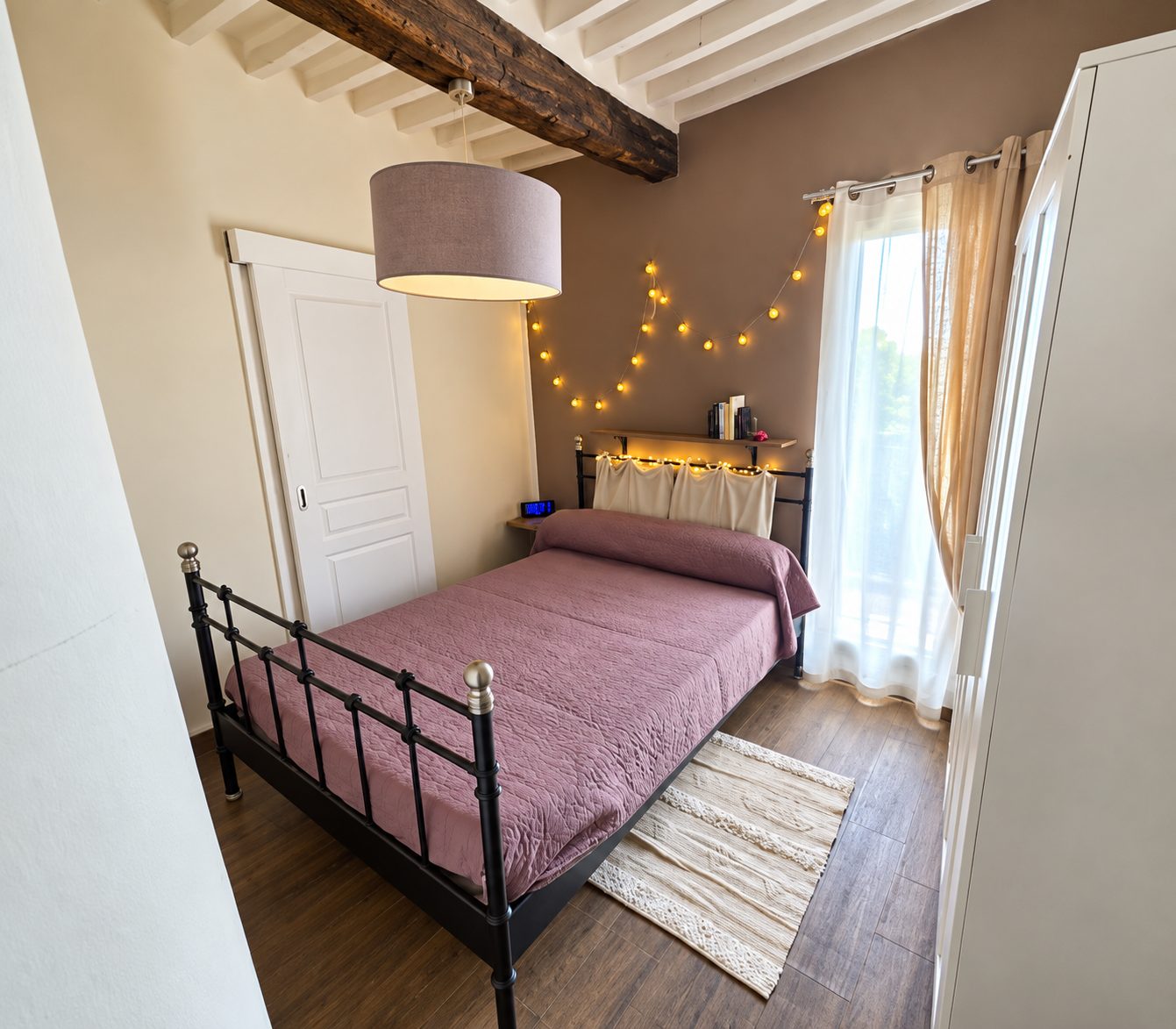 Chambre avec lit en fer forgé et guirlande lumineuse